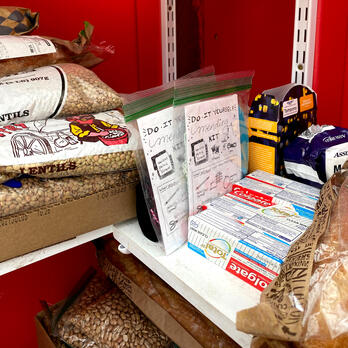 photo inside a neighborhood free fridge pantry, with food and hygiene items and a few mending kits