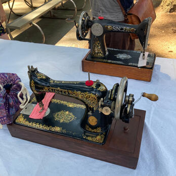 two very old sewing machines on a table outside